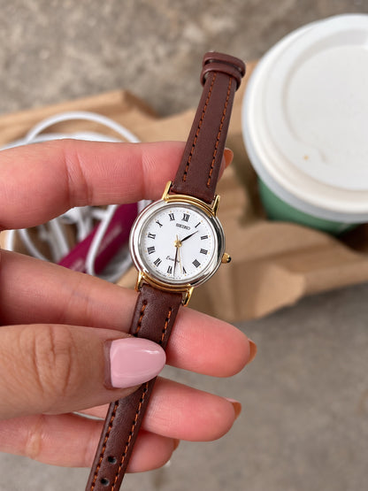 Seiko Exceline white Roman dial, two tone case and brown leather strap shown in hand.