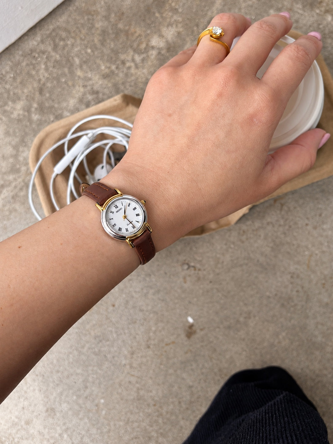 Seiko Exceline white Roman dial women's watch on wrist with a two tone round case and brown leather strap.