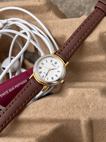 Seiko Exceline white Roman dial and silver tone bezel with gold tone lug details and dark crown tip.