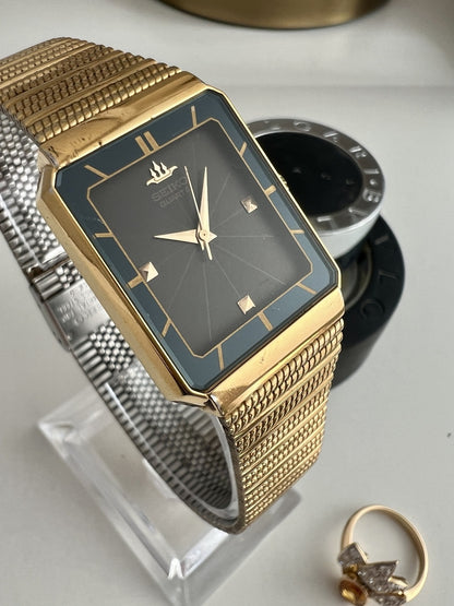 Close view of the Seiko Galaxy 8Y21-509A smoked black ray dial, petrol chapter ring, gold hands and faceted markers.