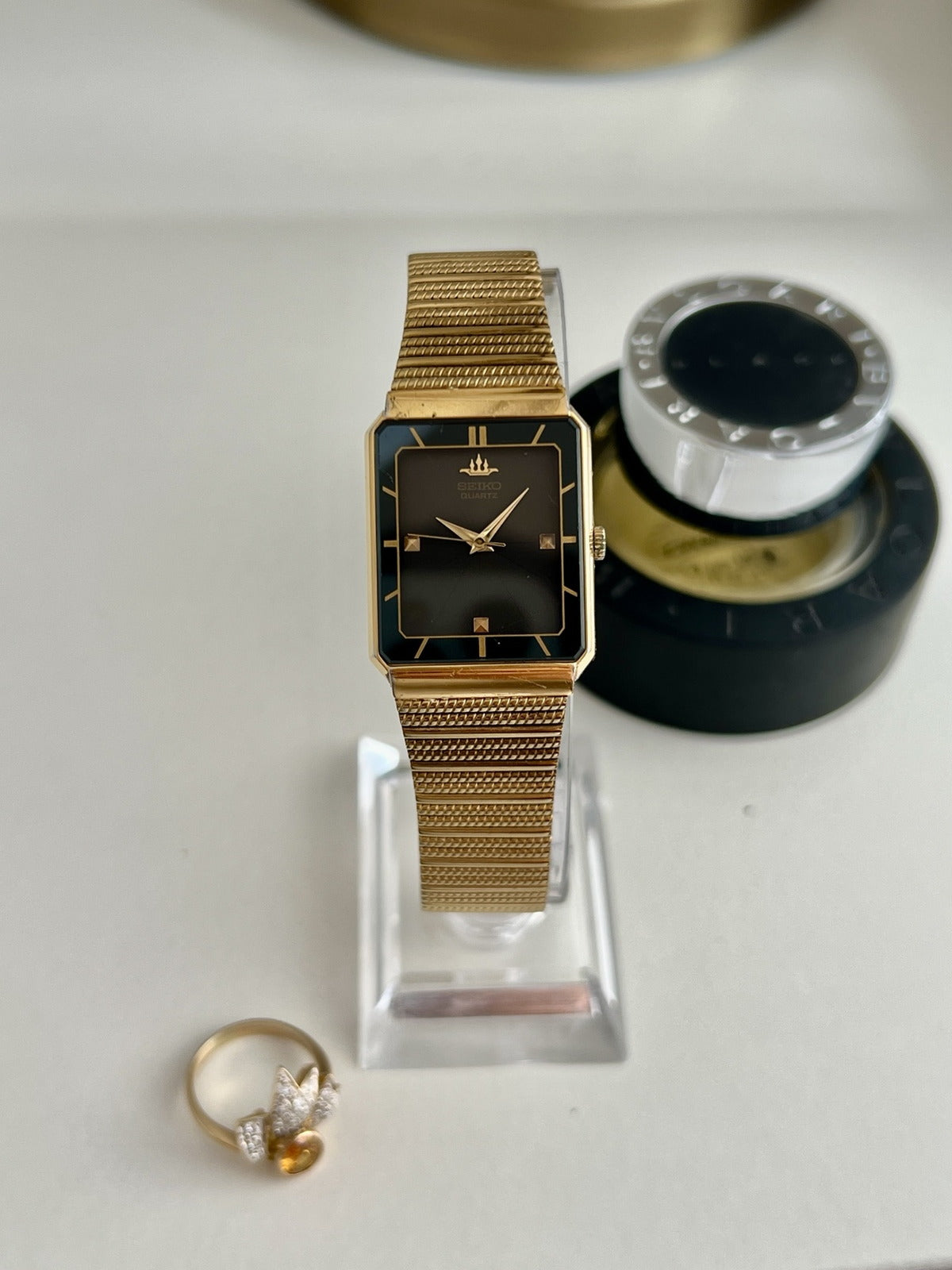 Seiko Galaxy women’s watch with a black ray dial, rectangular gold tone case and textured bracelet, shown front on.