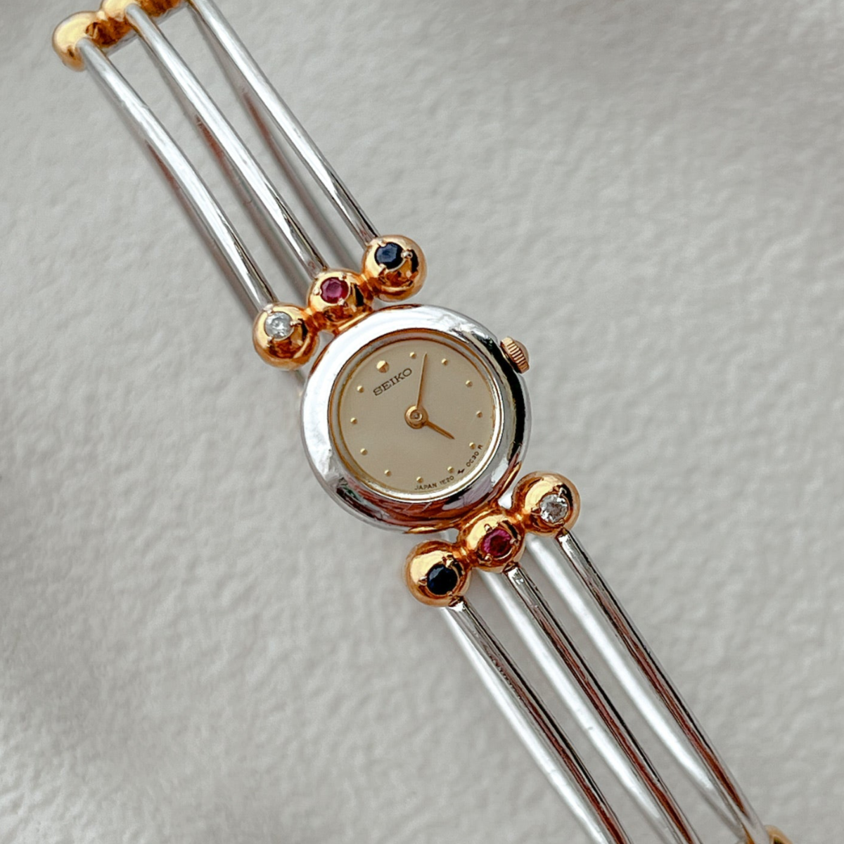 Seiko Tissé two-tone bangle watch with a champagne dial and ruby, sapphire and clear crystal accents; product image 2.