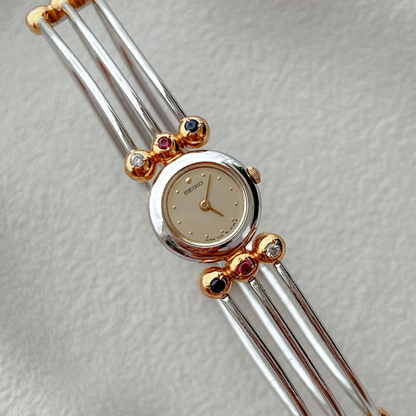 Seiko Tissé two-tone bangle watch with a champagne dial and ruby, sapphire and clear crystal accents; product image 2.