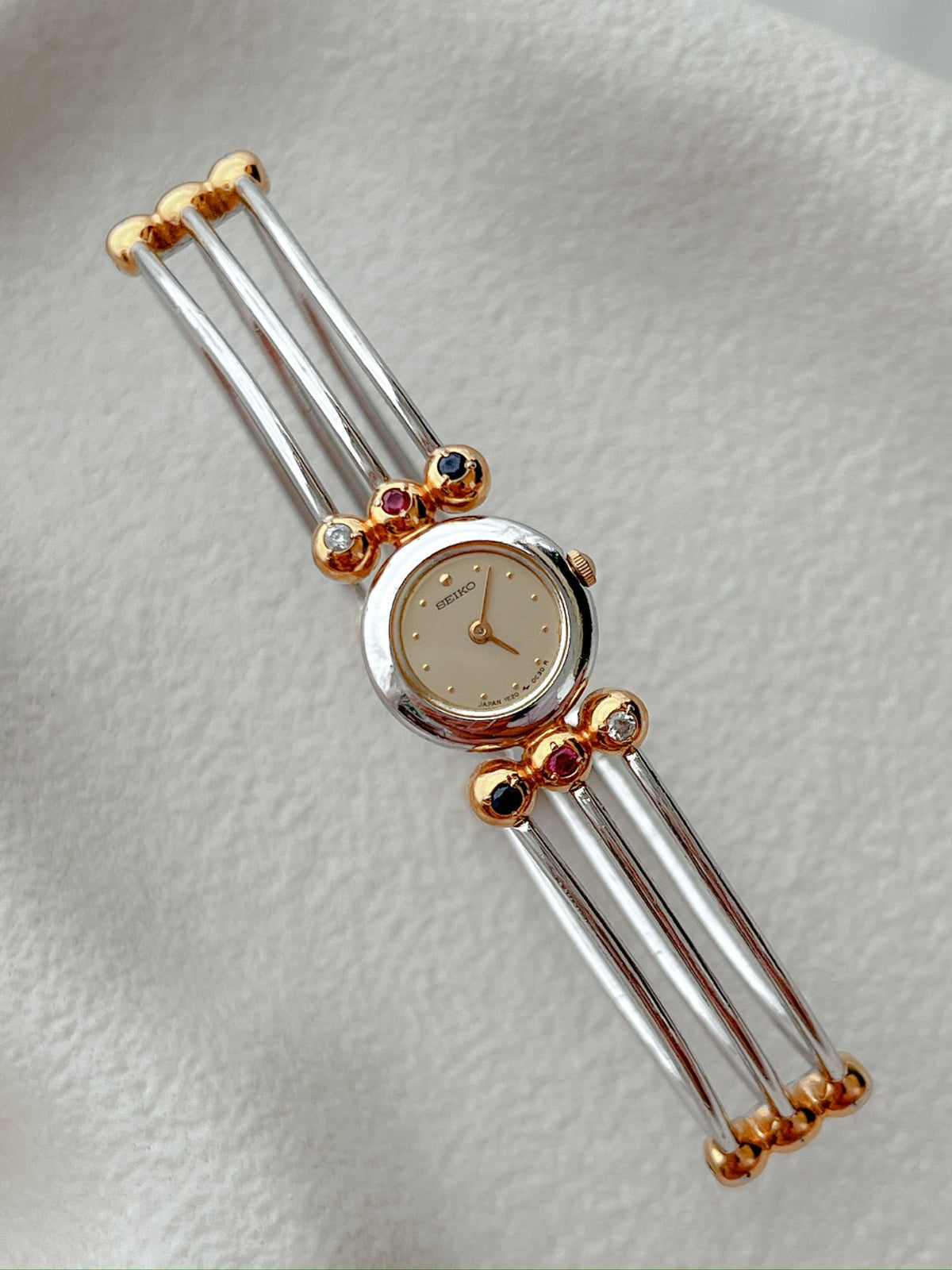 Seiko Tissé two-tone bangle watch with a champagne dial and ruby, sapphire and clear crystal accents; product image 3.