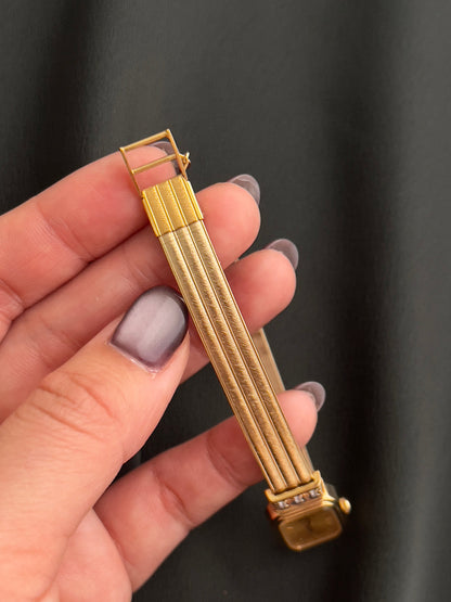 Detail of the brushed gold-tone integrated bracelet and crystal-set case edge.