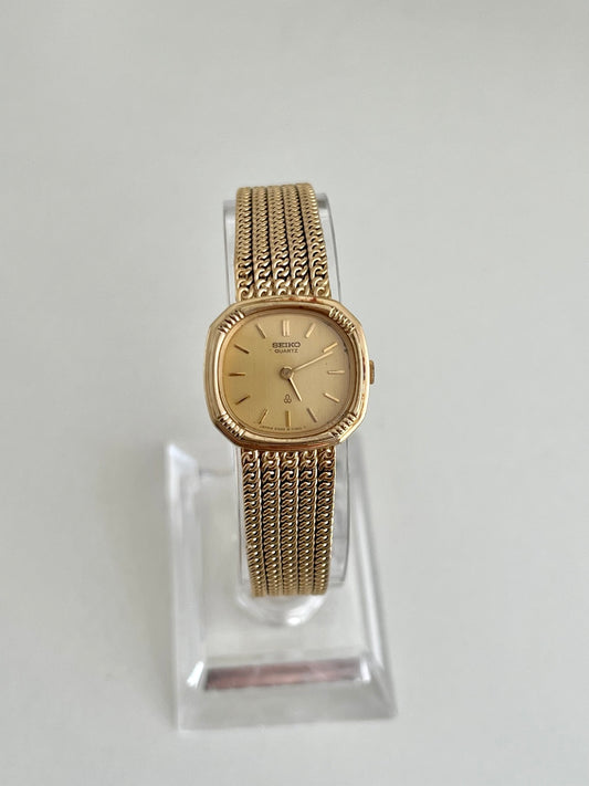 Front view of Seiko gold tone cushion watch with champagne dial and five row chain bracelet