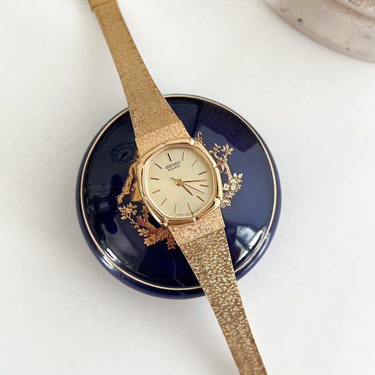 Seiko gold cushion women’s watch with textured bracelet, front view.