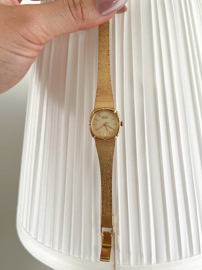 Seiko Gold Cushion Tatami Bracelet Women’s Watch — Held full watch in front of a pale curtain