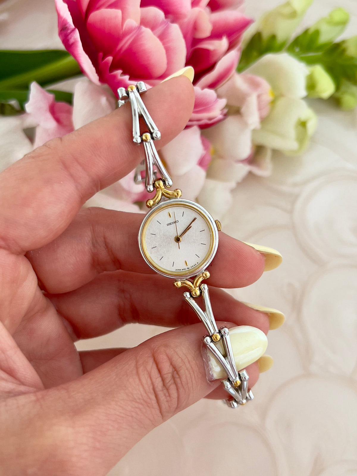 Seiko Two Tone Women’s Watch with White Dial and Sculpted Bracelet — watch held in the hand.