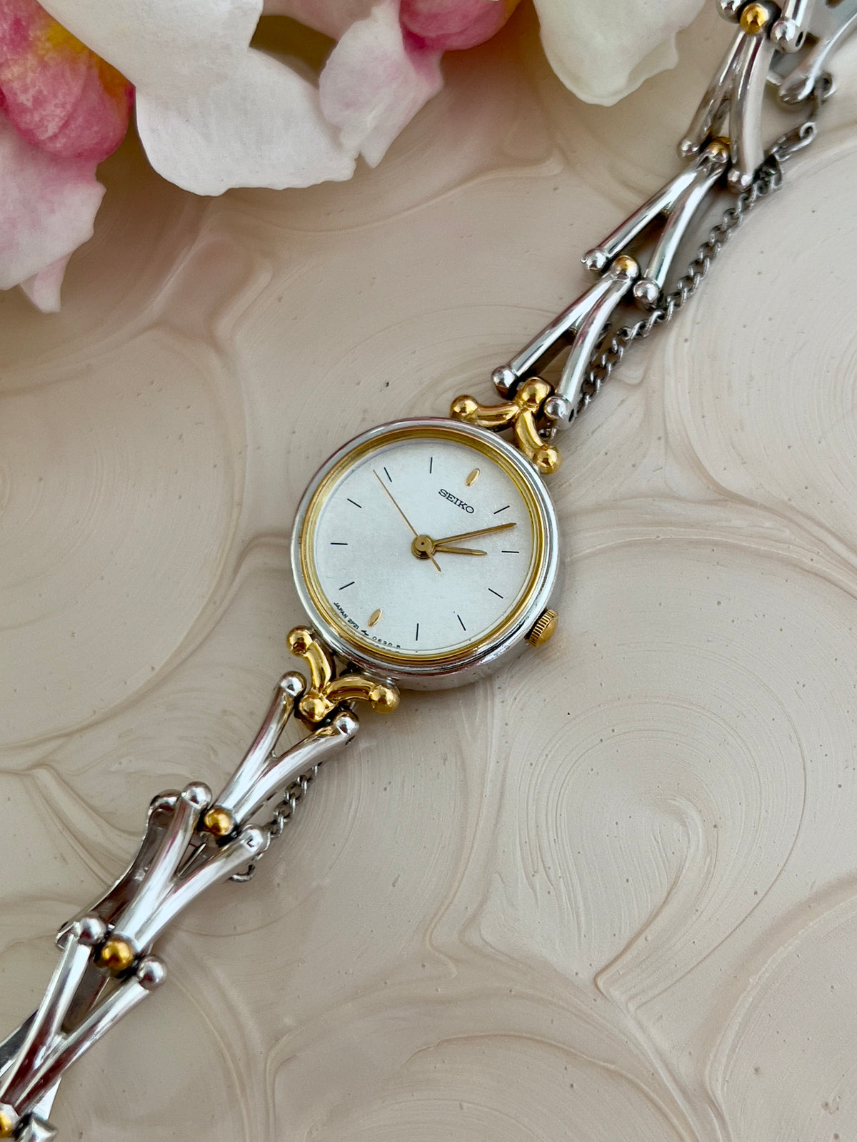 Seiko Two Tone Women’s Watch with White Dial and Sculpted Bracelet — angled view of dial and bezel.
