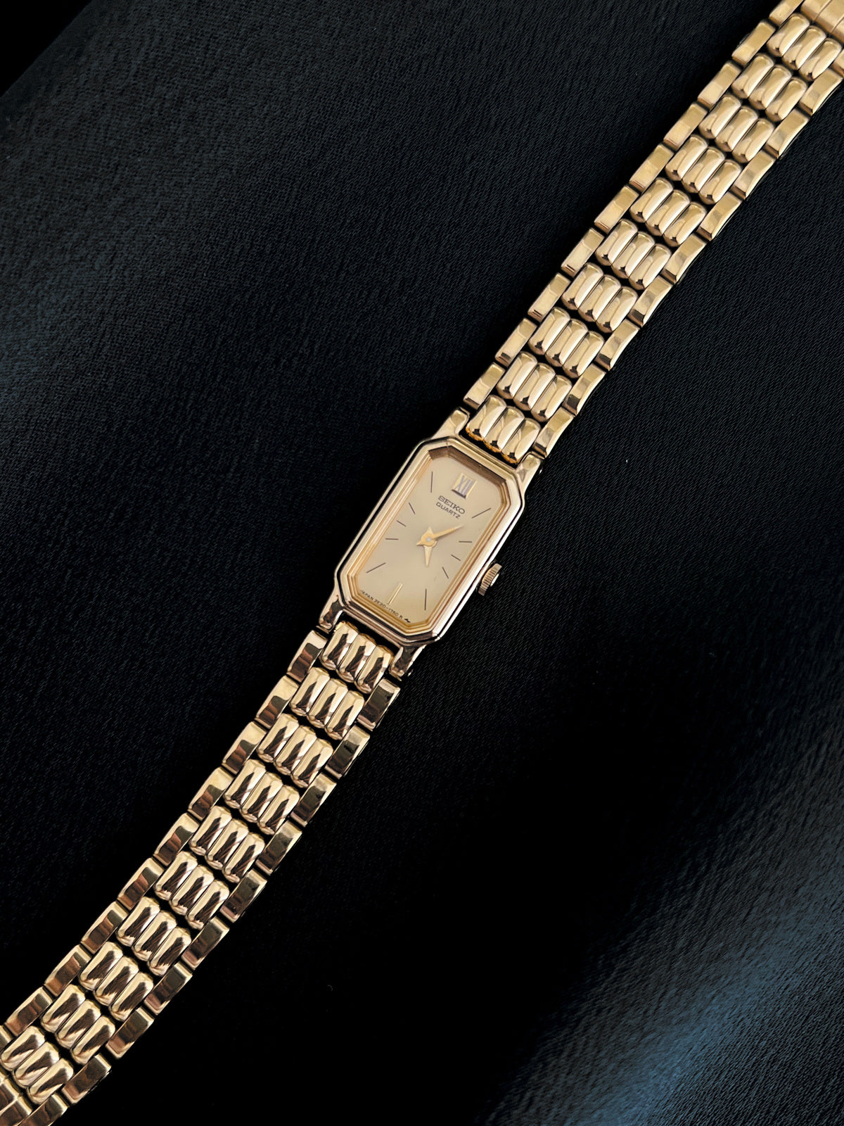 Angled detail of Seiko champagne dial, gold-tone case and bracelet