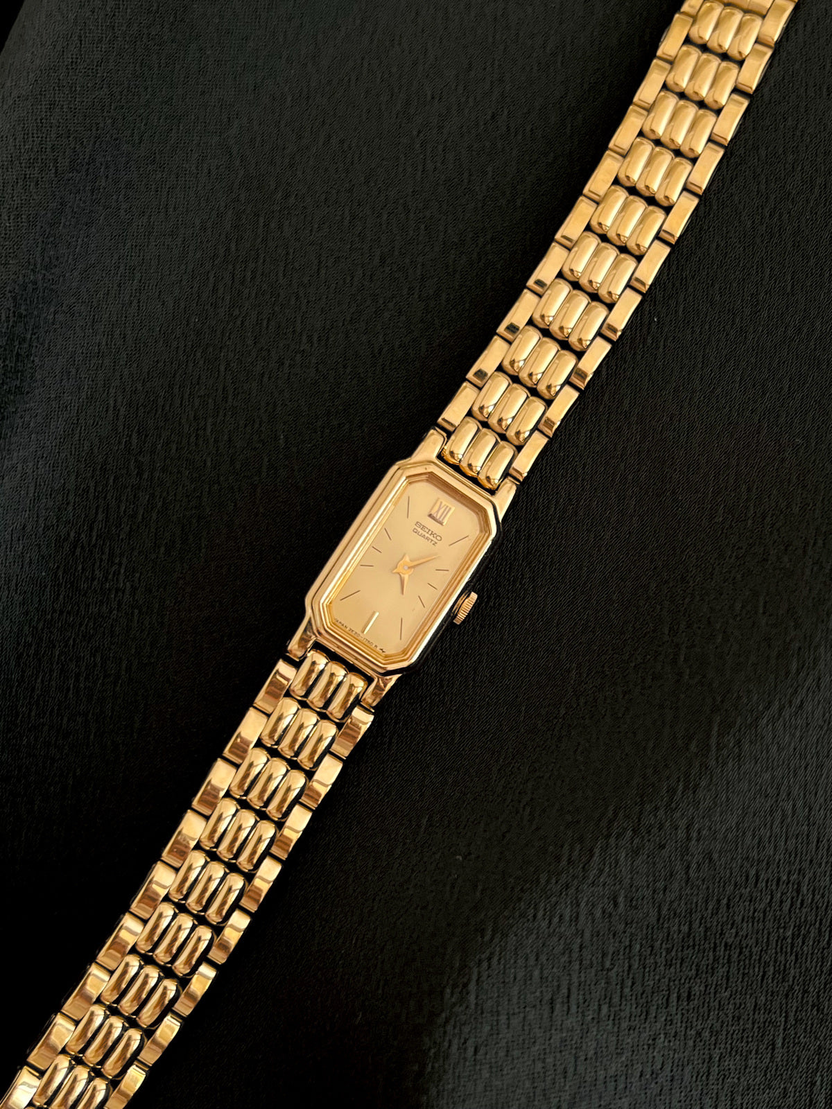 Three-quarter front view of the Seiko gold-tone watch and articulated bracelet