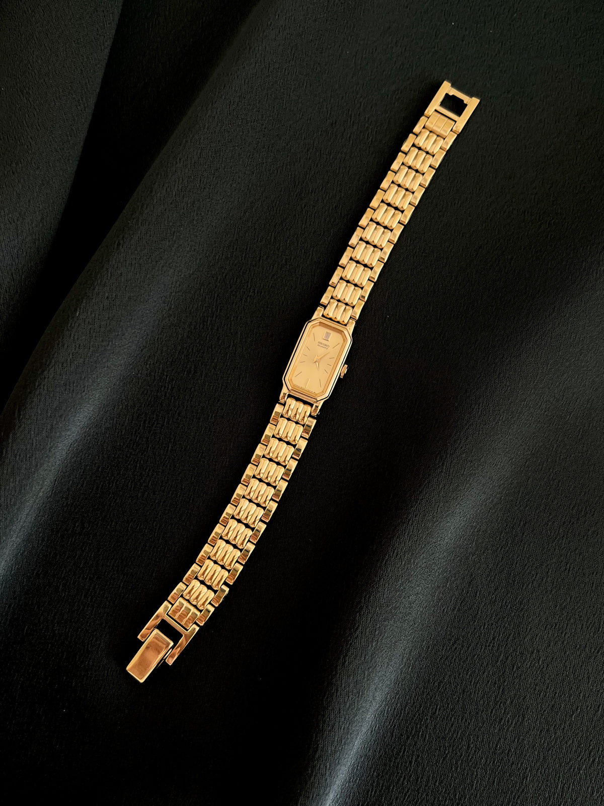 Seiko gold-tone women’s watch with champagne dial and articulated bracelet, full front view