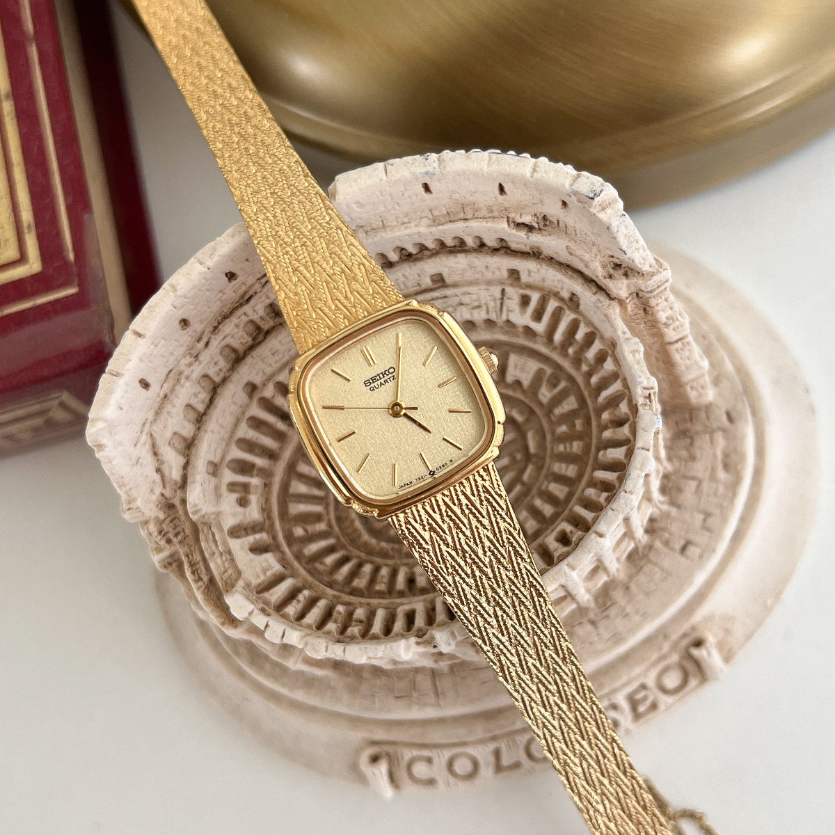 Seiko Gold Cushion Textured Bracelet Women’s Watch — Dial and textured bracelet displayed across a decorative bowl