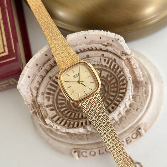 Seiko gold toned women’s watch with textured bracelet, front view.