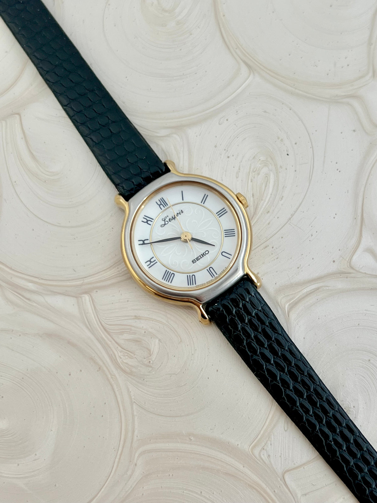 Close-up of the Seiko L'Espoir pearl-white dial with Roman numerals and scroll motif.