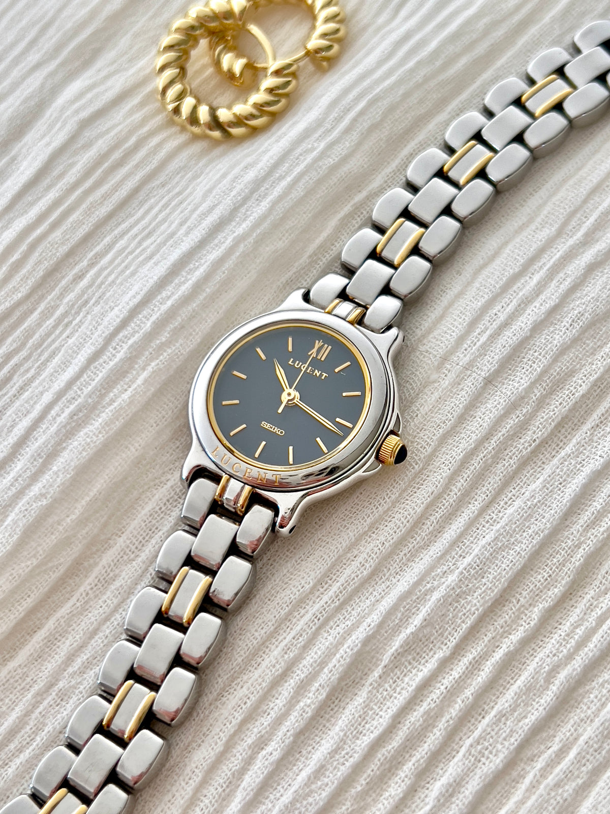 Angled flat-lay of the Seiko Lucent 1F21-0G90 navy dial and two-tone bracelet