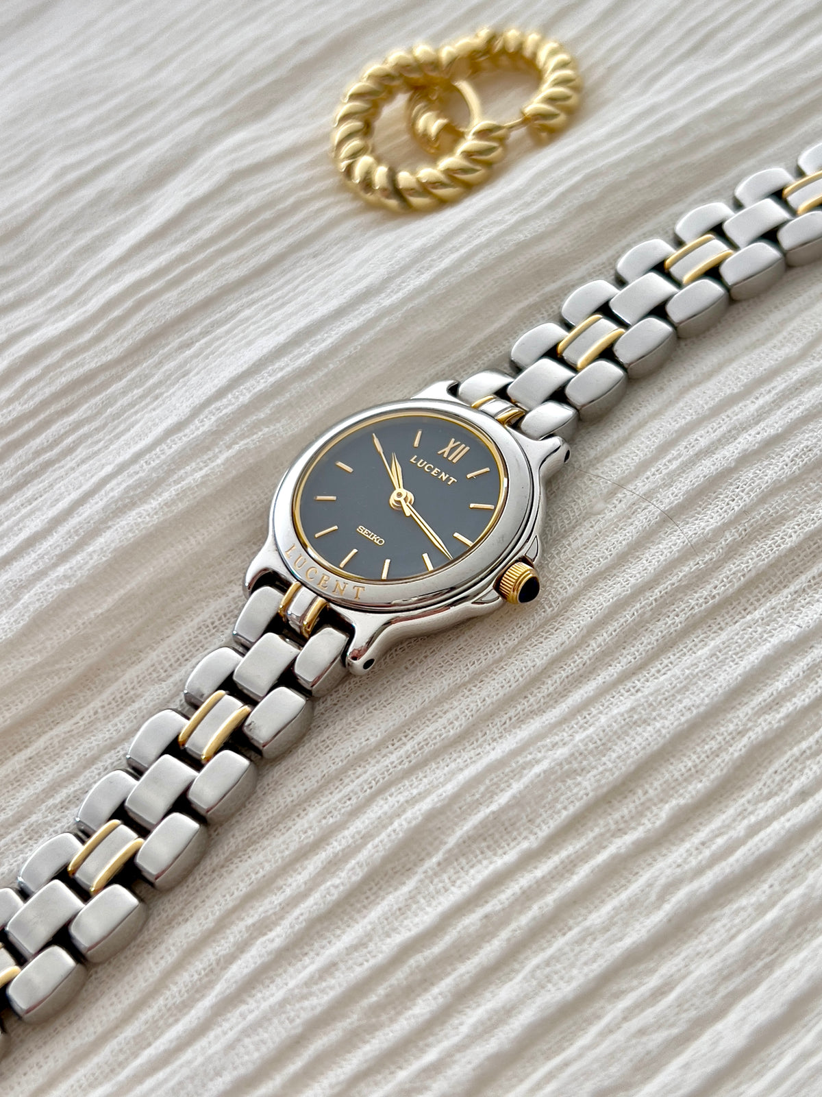 Angled view of the Seiko Lucent 1F21-0G90 navy dial, gold-tone crown and two-tone bracelet