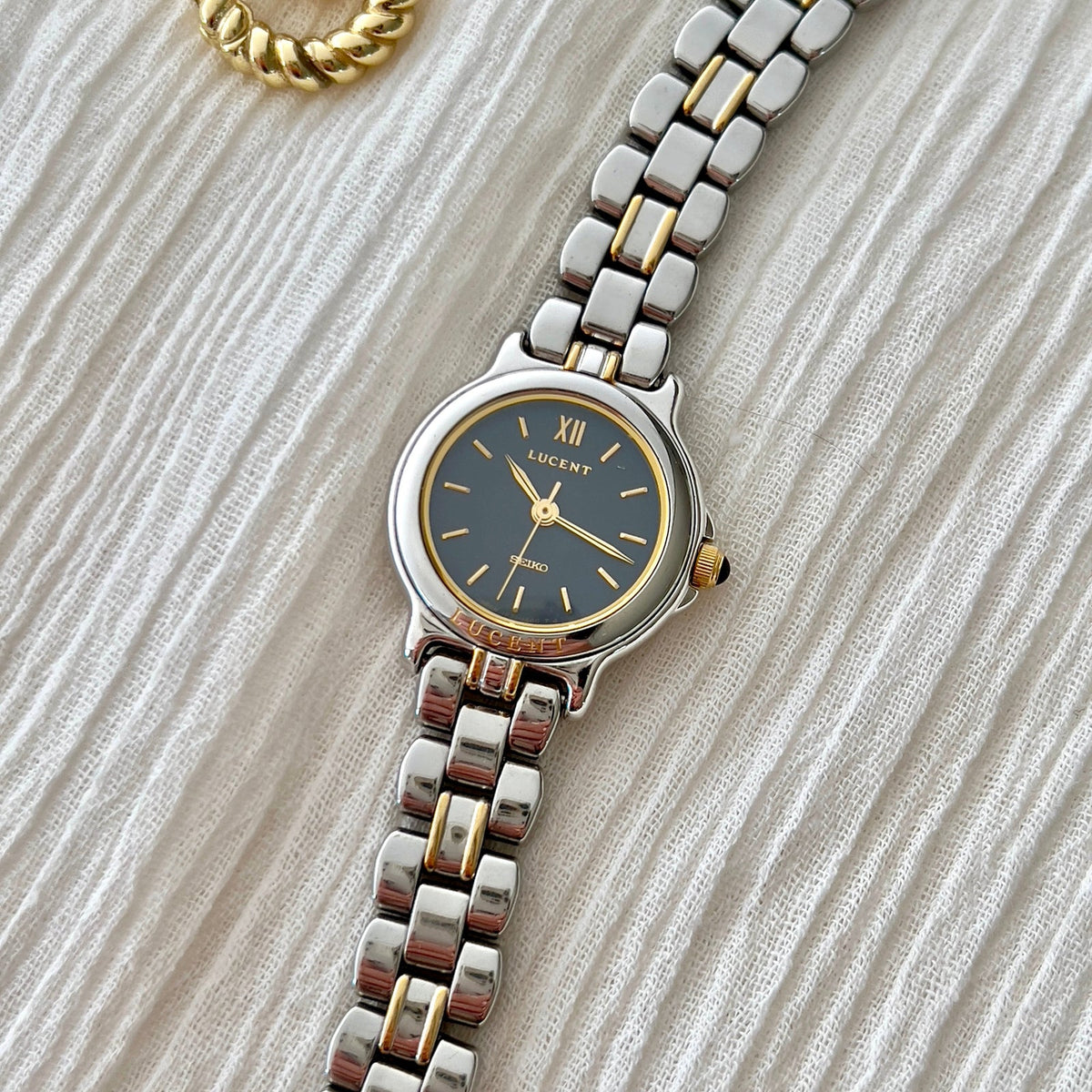 Close-up of the Seiko Lucent 1F21-0G90 navy dial, gold Roman XII and two-tone bracelet