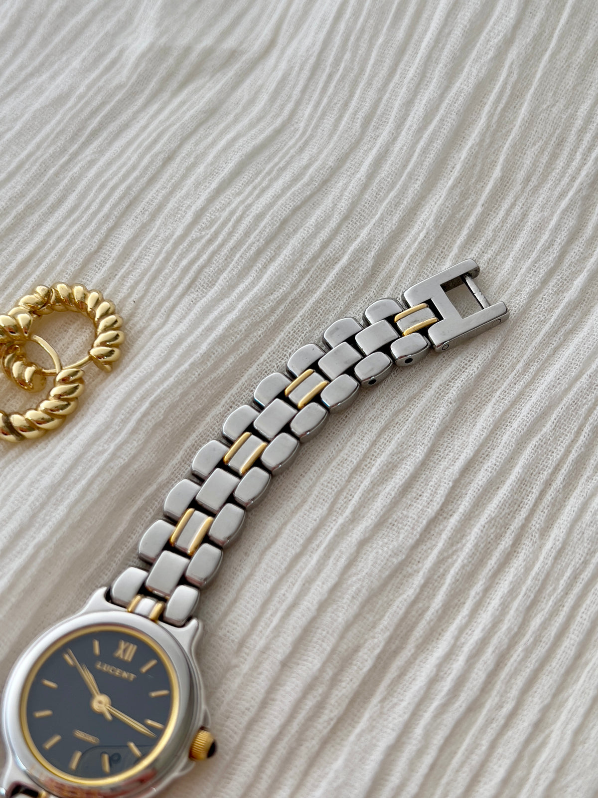 Two-tone bracelet links and clasp of the Seiko Lucent 1F21-0G90, with part of the navy dial visible