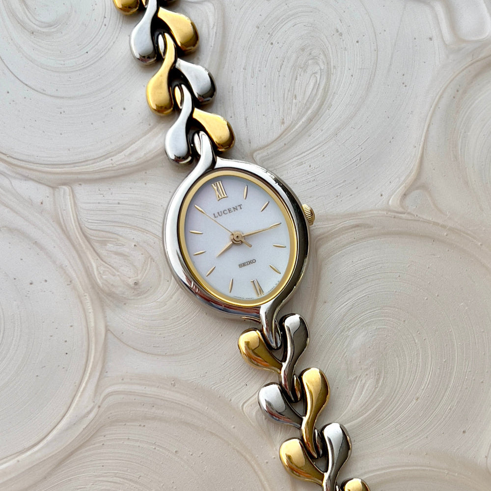 Seiko Lucent oval dial and silver-and-gold heart-link bracelet laid flat