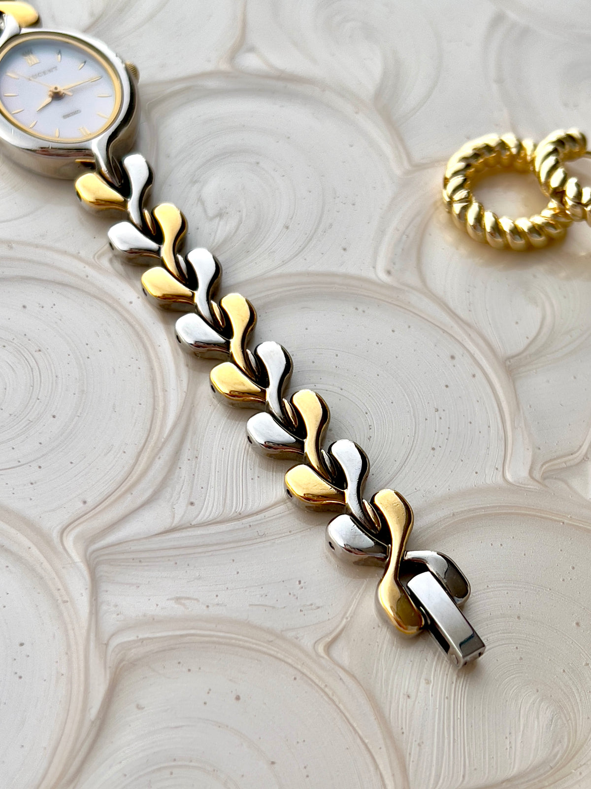 Seiko Lucent two-tone bracelet and clasp detail on a cream backdrop