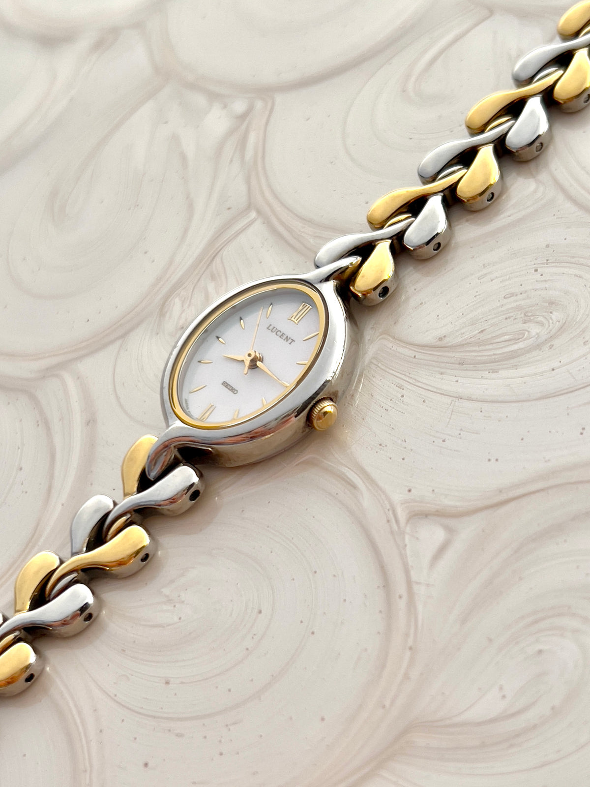 Angled view of Seiko Lucent oval case, pearlescent dial and two-tone links