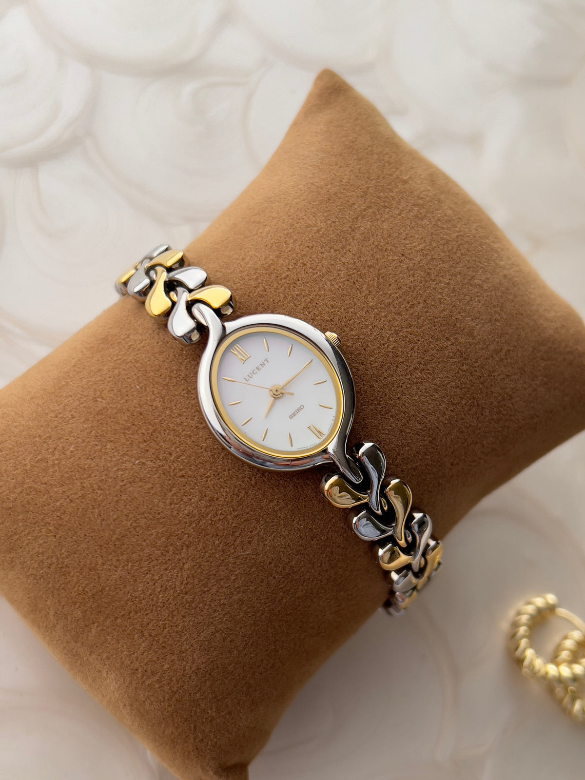 Seiko Lucent pearlescent dial watch displayed on a tan cushion