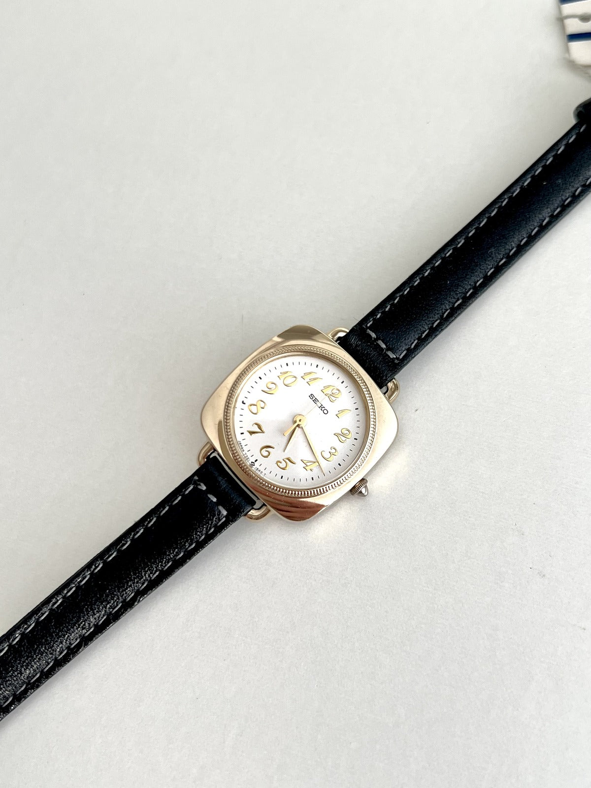 Angled front view of the Seiko Nouveau 7321-0340 showing its polished gold tone cushion case and round white dial.