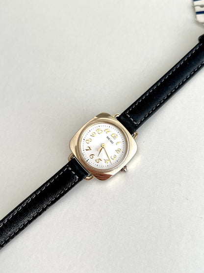 Angled front view of the Seiko Nouveau 7321-0340 showing its polished gold tone cushion case and round white dial.