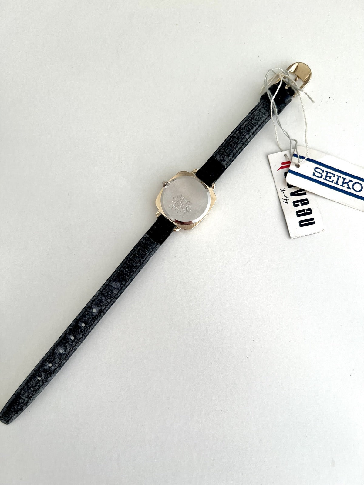Rear view of the Seiko Nouveau 7321-0340 with stainless steel caseback, Seiko-signed leather strap and attached hang tags.