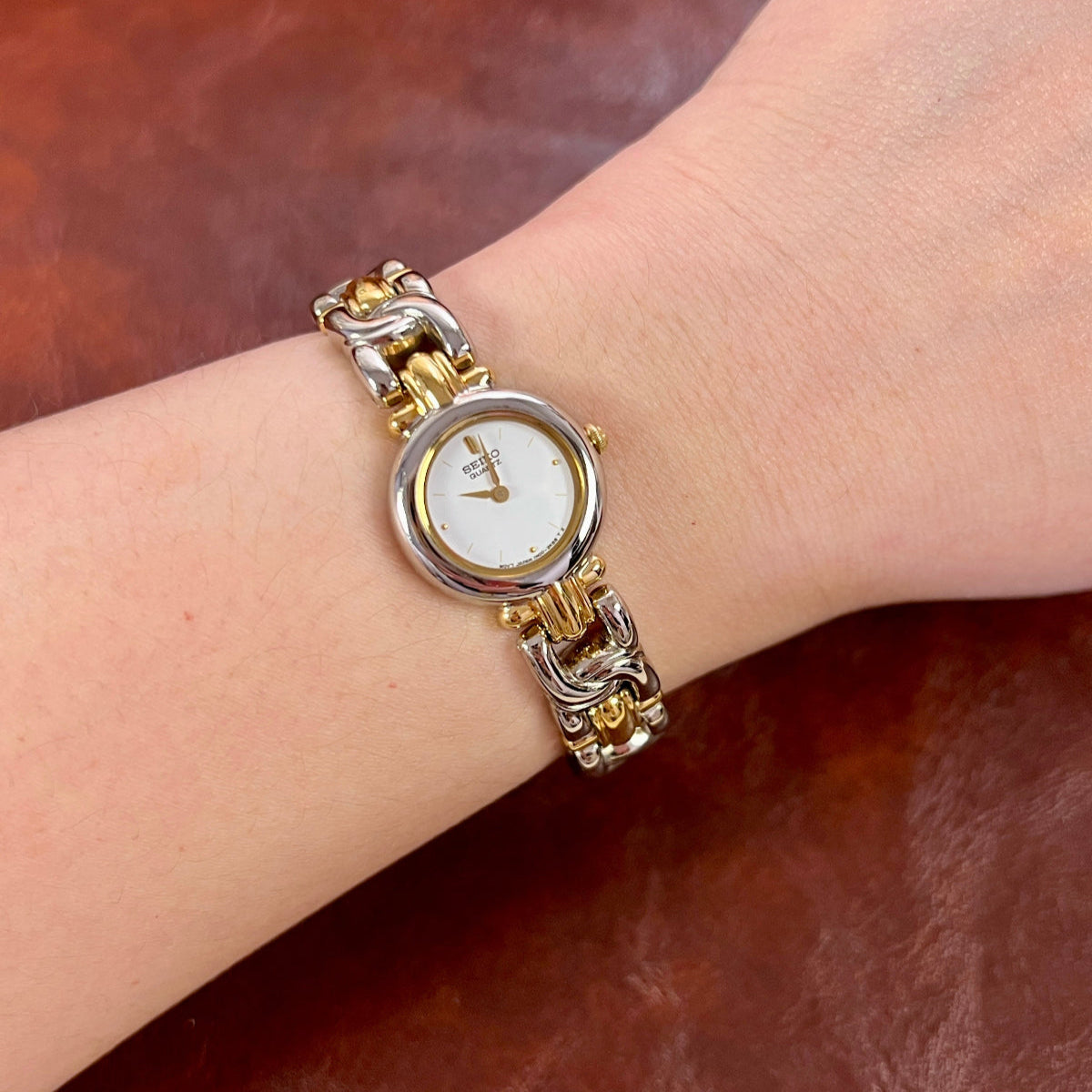 Seiko petite two-tone women's watch with a white guilloche dial and sculpted bracelet.