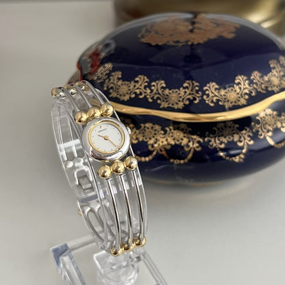 Seiko two-tone women’s bangle watch with white dial and gold bead accents, angled front view