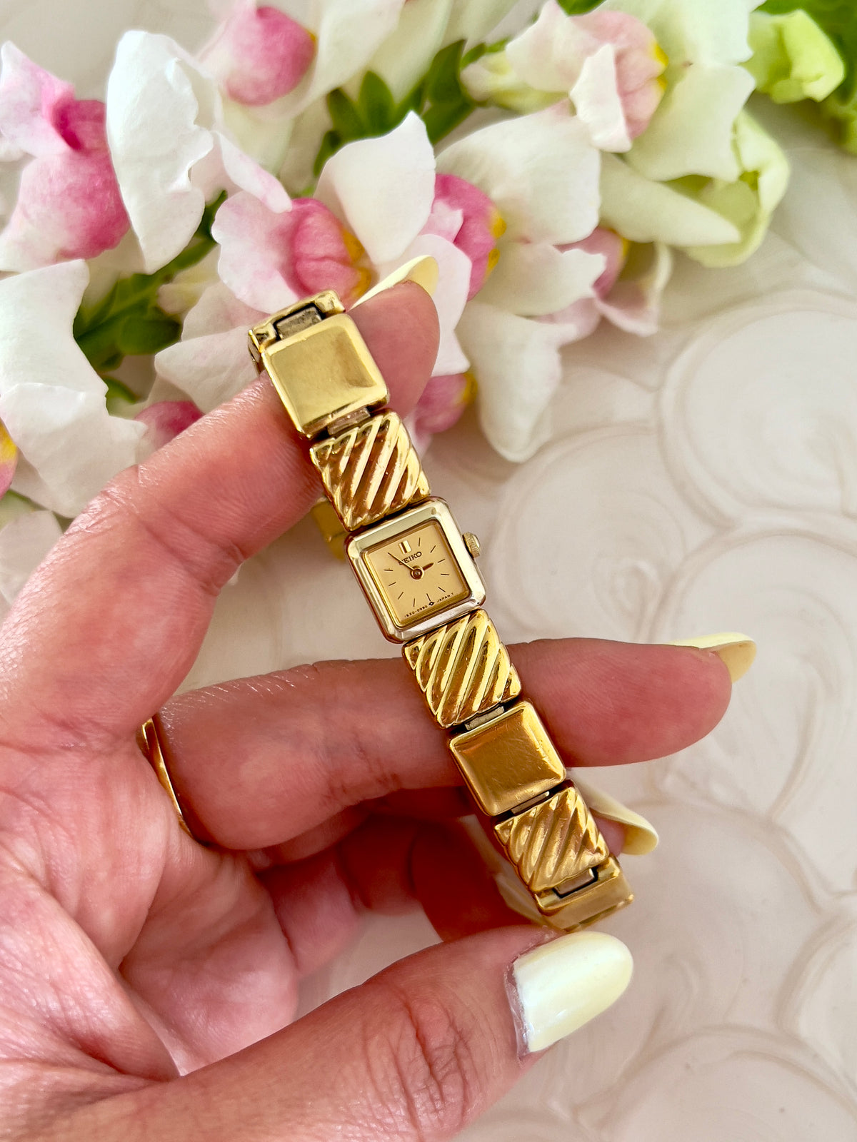 Close-up of the square gold-tone dial on the Seiko watch.
