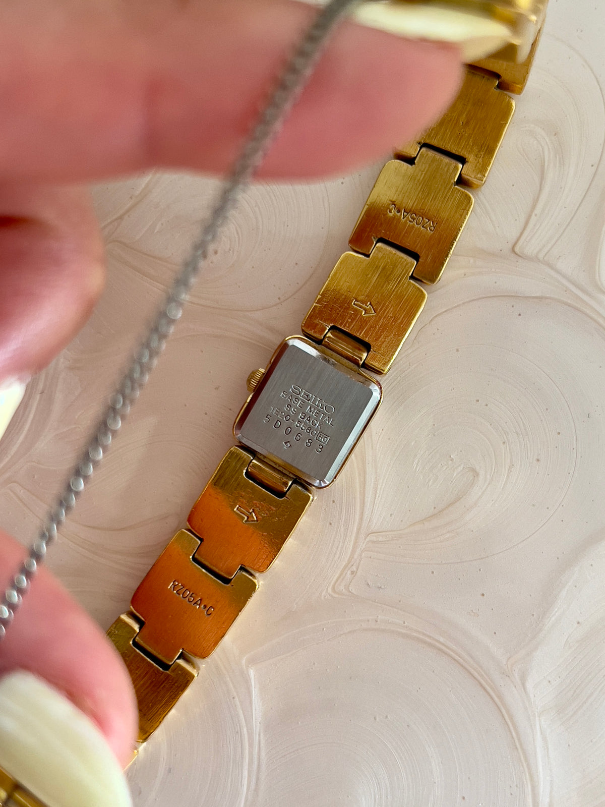 Seiko square gold-tone bracelet watch pictured on a wrist.