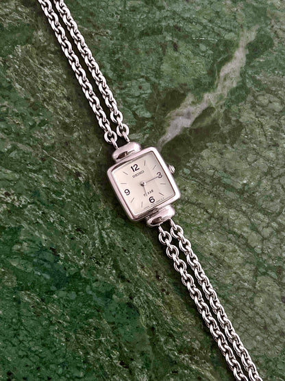 Seiko Tissé double-strand silver bracelet watch shown on a wrist.