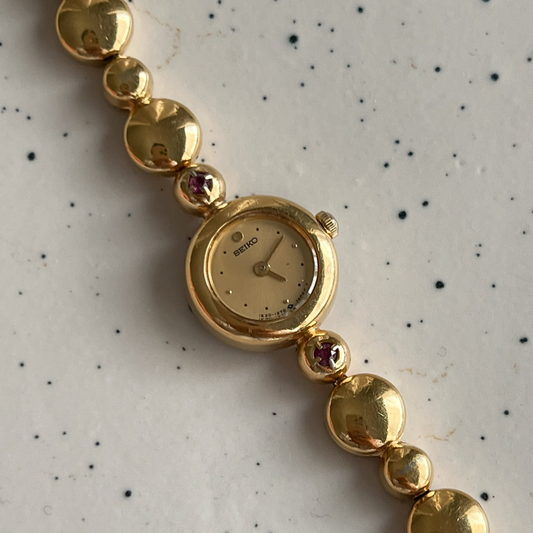 Seiko Tissé Ruby Accent Bubble Bracelet Women’s Watch featuring champagne dial; vintage watch product image 1.