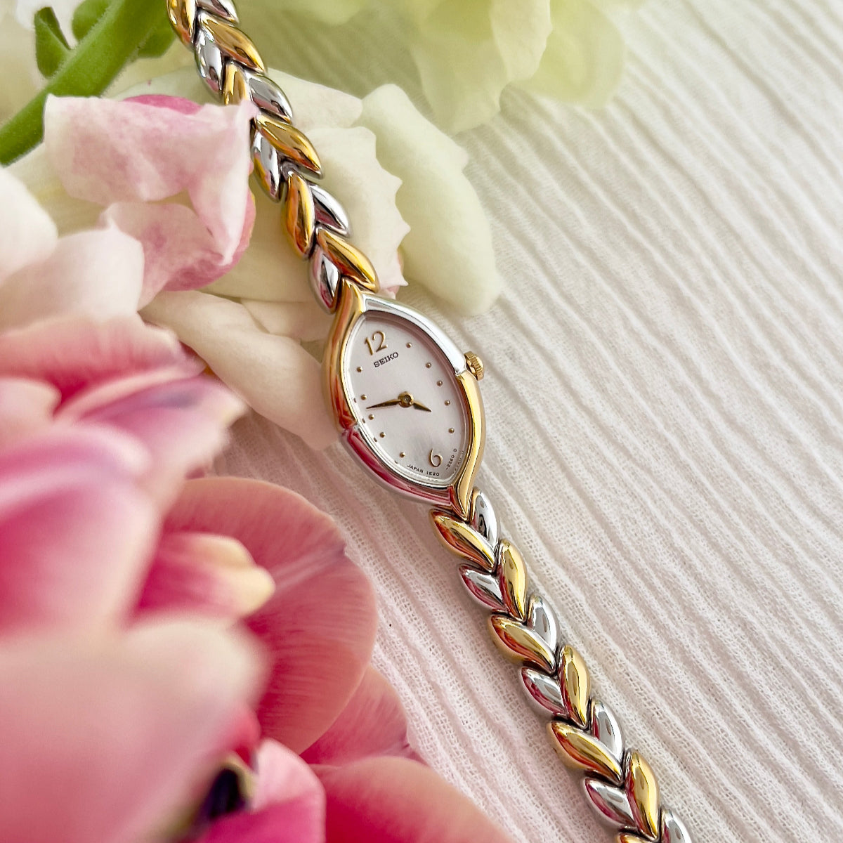 Seiko Tisse women's teardrop watch with white dial and two-tone leaf-link bracelet.