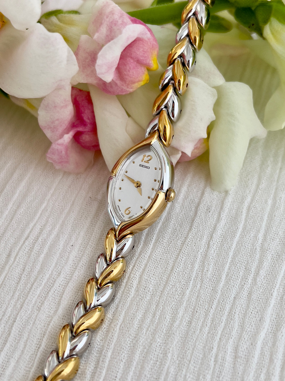 Seiko two-tone teardrop watch shown on a wrist.