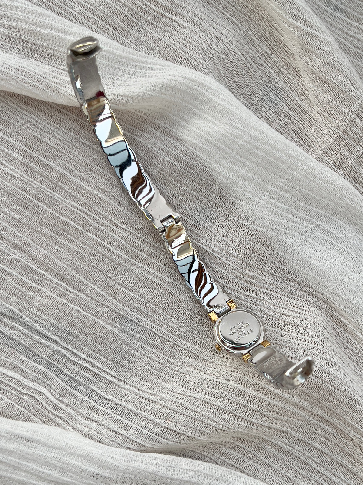 Seiko Bangle Woman's Watch – Two-Tone with Sapphire and Diamond Accents — detail of the case and band.