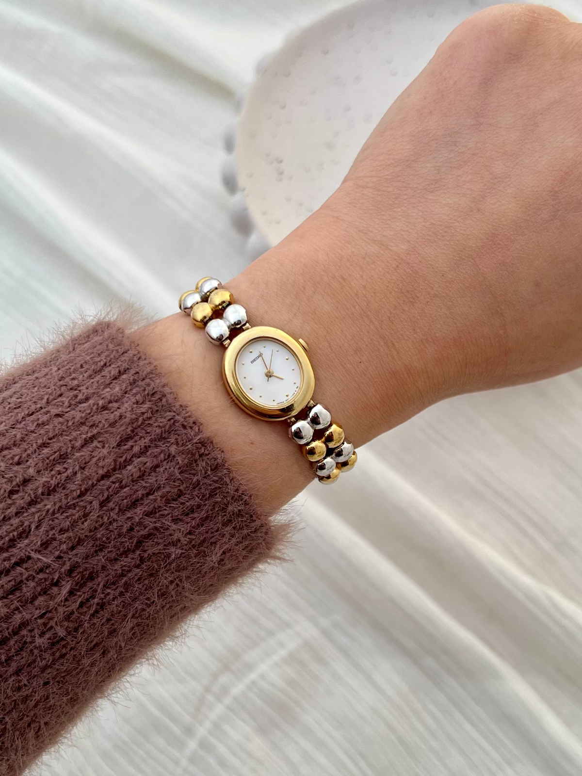 Side profile of the Seiko two-tone oval watch case and double-bead bracelet.