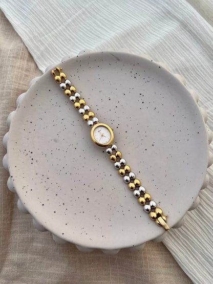Close-up of the white dial, gilt hands and dot hour markers on the Seiko oval watch.