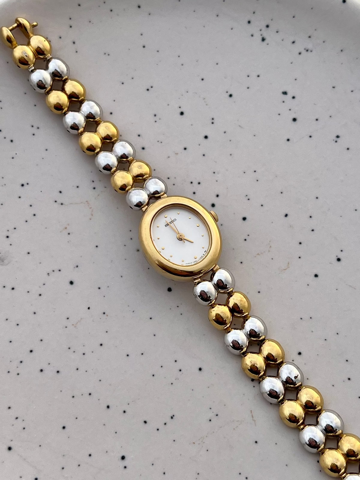 Angled view of the Seiko oval watch case and two-tone bead bracelet.