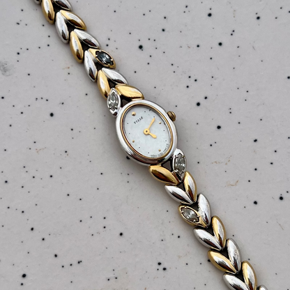 Close-up of the Seiko two-tone oval watch's mother-of-pearl dial and gold markers.