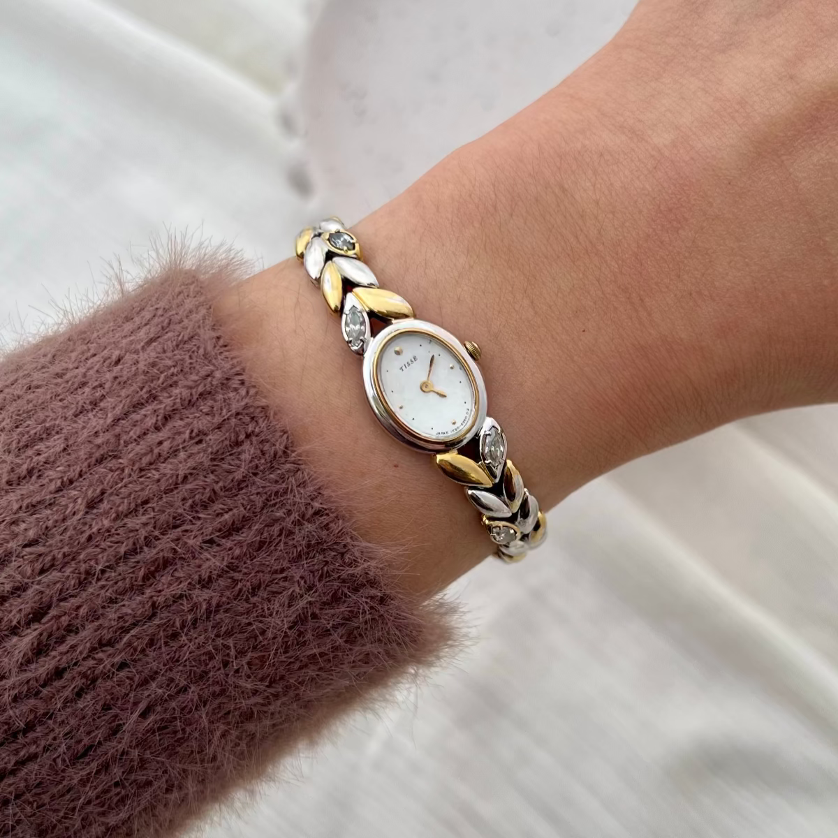 Front view of the Seiko two-tone oval watch with mother-of-pearl dial and gem-set sculpted bracelet.