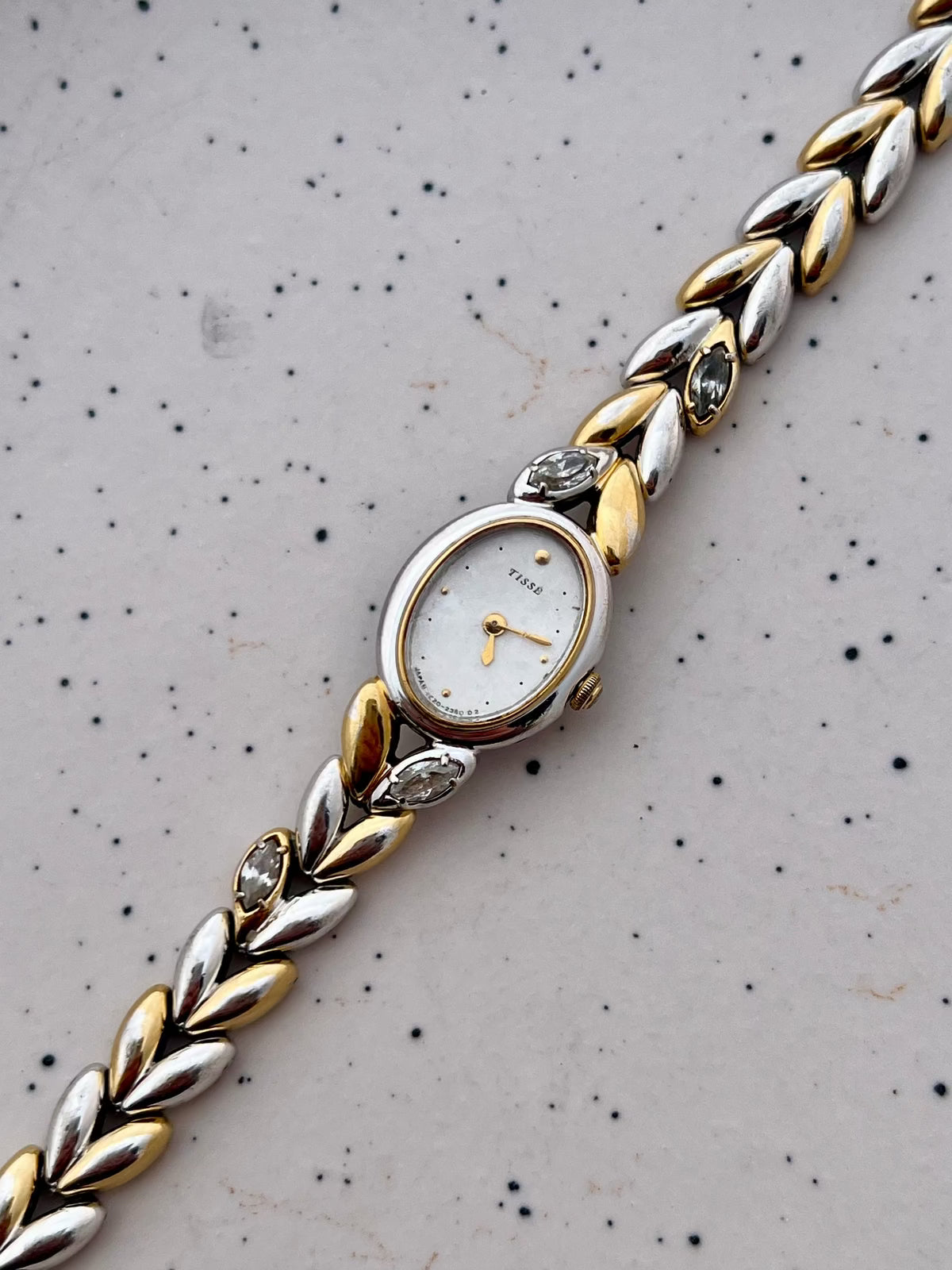 Angled view of the Seiko oval case and two-tone sculpted bracelet with embedded stones.