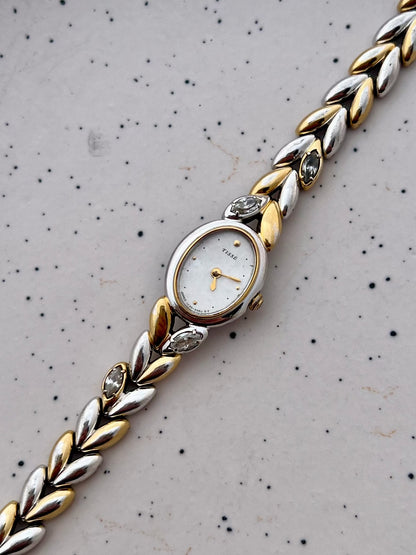 Angled view of the Seiko oval case and two-tone sculpted bracelet with embedded stones.