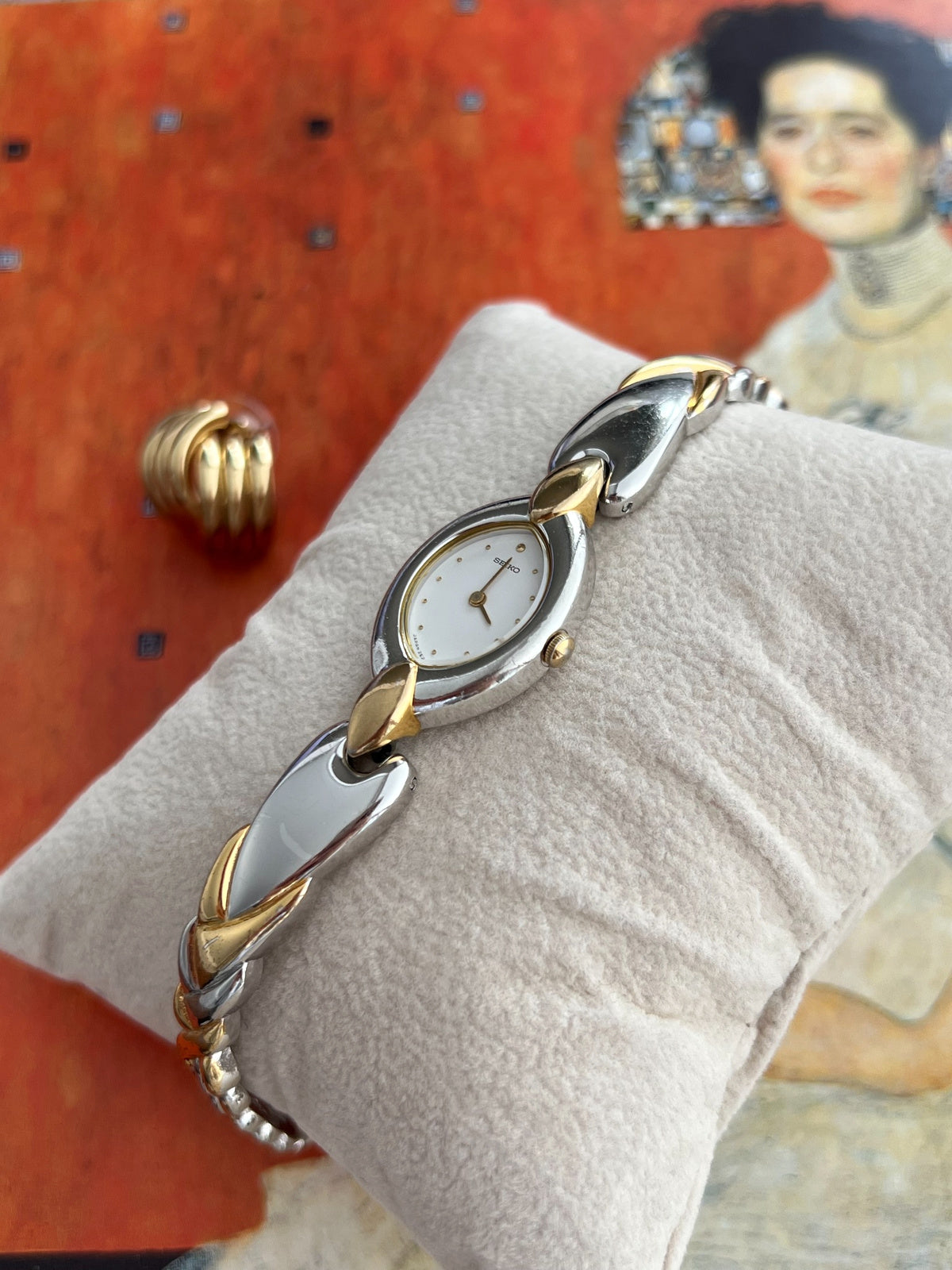 Angled view of the Seiko oval watch showing the gold tone crown and sculpted two tone bracelet
