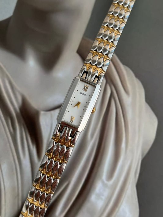 Seiko two-tone rectangular watch with white dial, gold markers and sculpted bracelet.