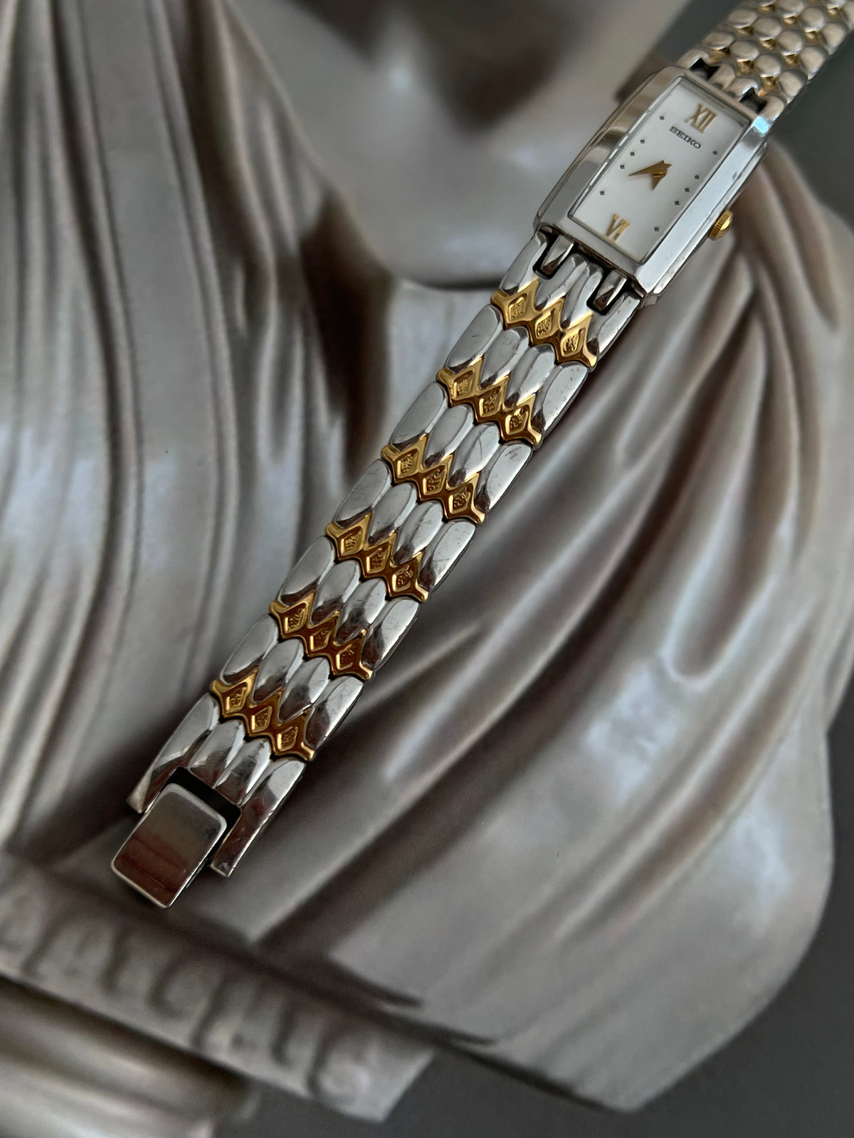 Seiko rectangular watch with gold-tone case and two-tone bracelet.